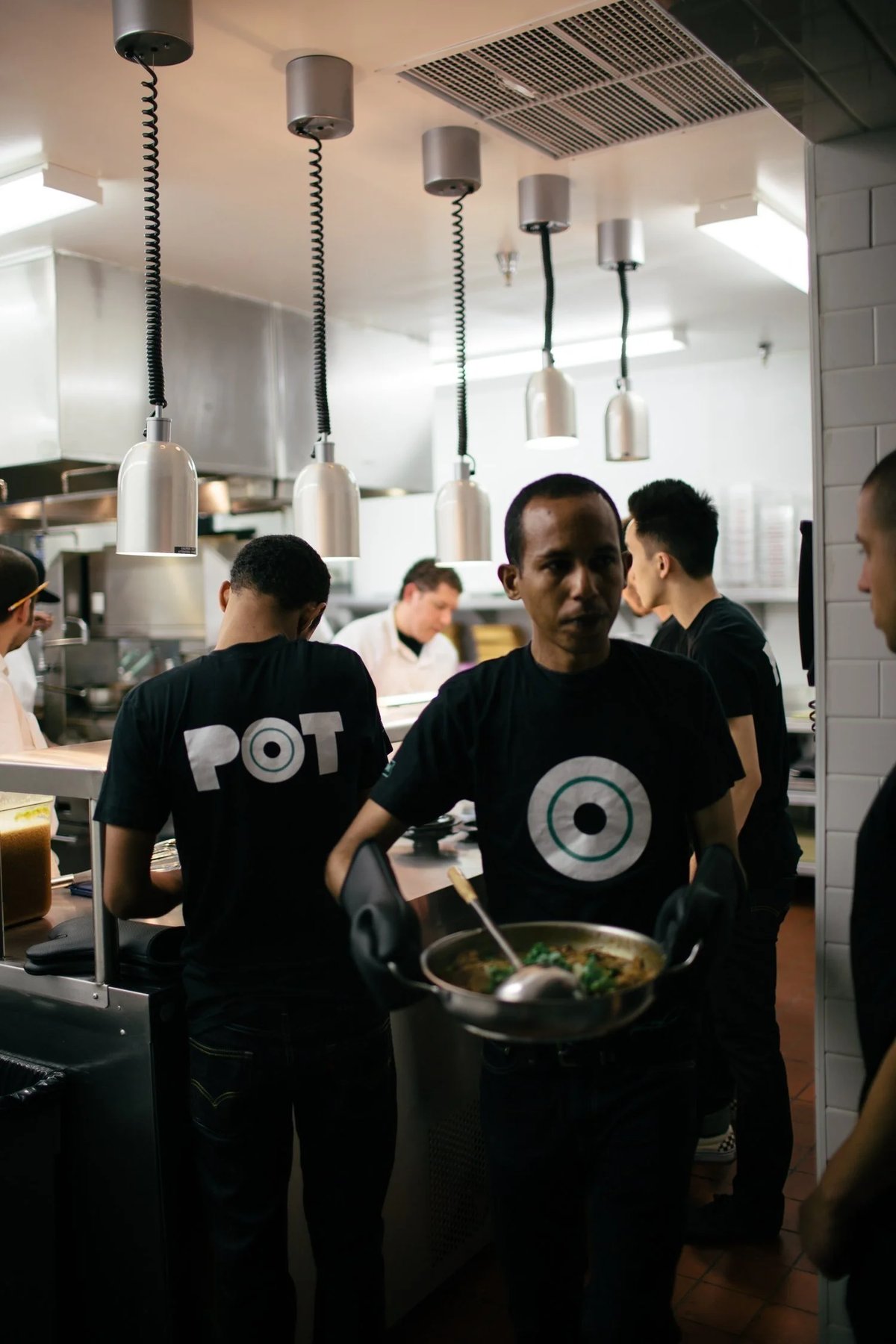 Server wearing black restaurant uniform shirt Pot by Finery.