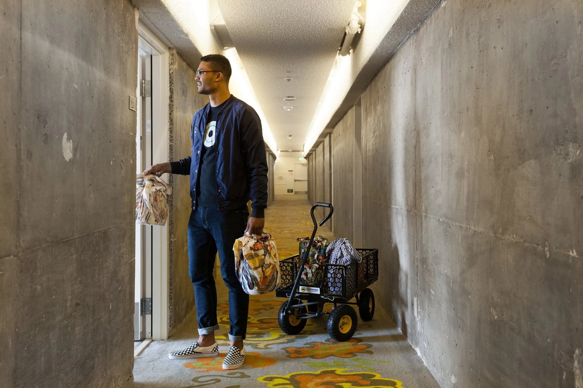 Delivery man wearing a blue restaurant uniform bomber jacket Roy Choi by Finery.