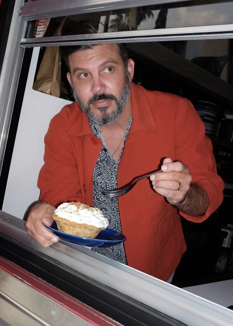 Man eating and wearing the custom All Day Baby workwear coats designed by Finery.
