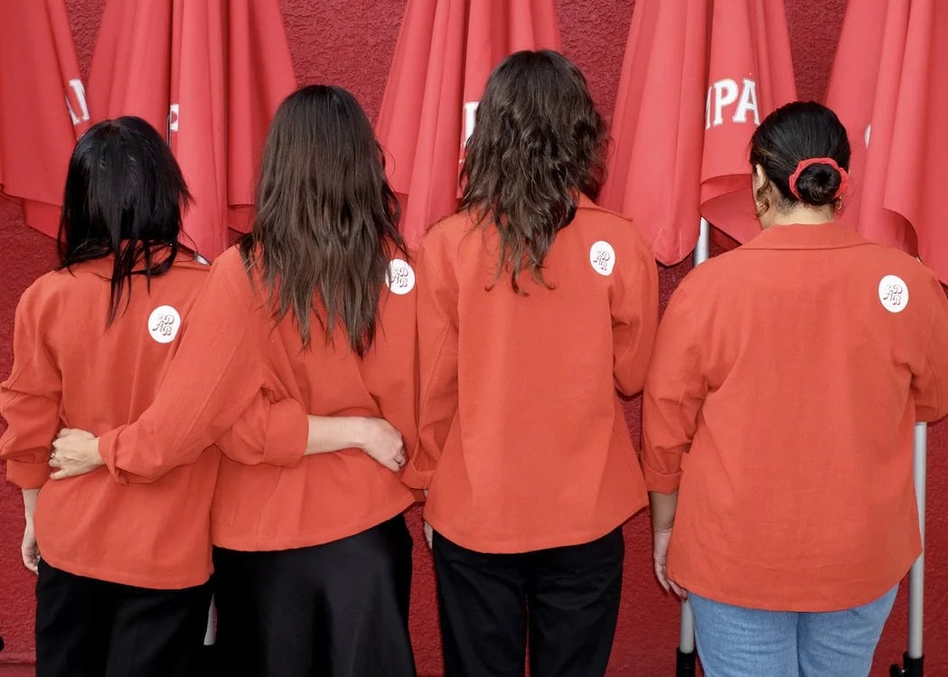 Four people facing away wearing the custom All Day Baby workwear coats designed by Finery.