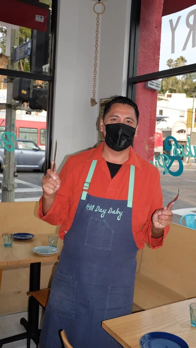 Man in apron wearing the custom All Day Baby workwear coats designed by Finery.