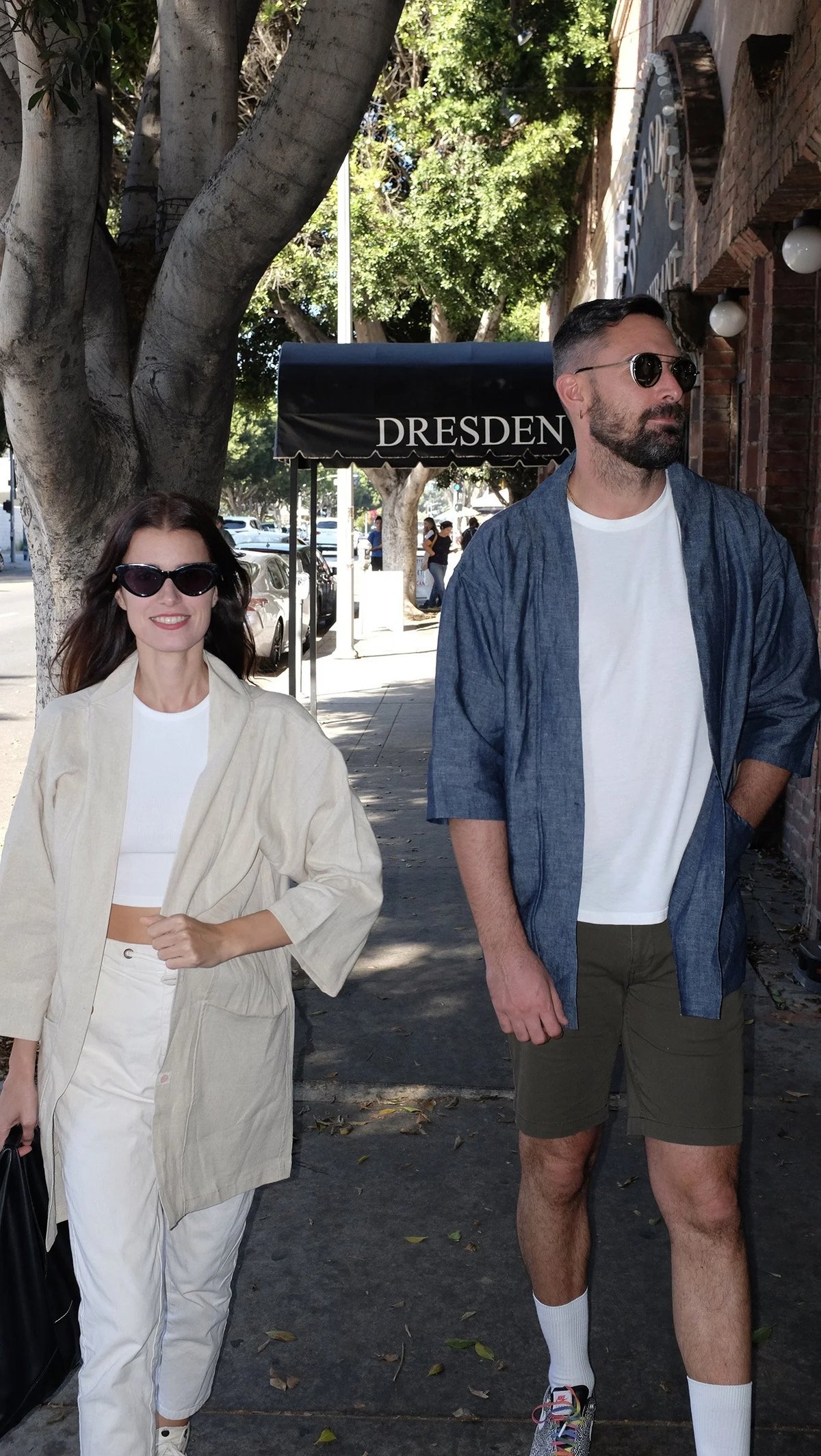 A pair walking wearing Proper Hotels kimono coat in oatmeal and indigo designed by Finery.