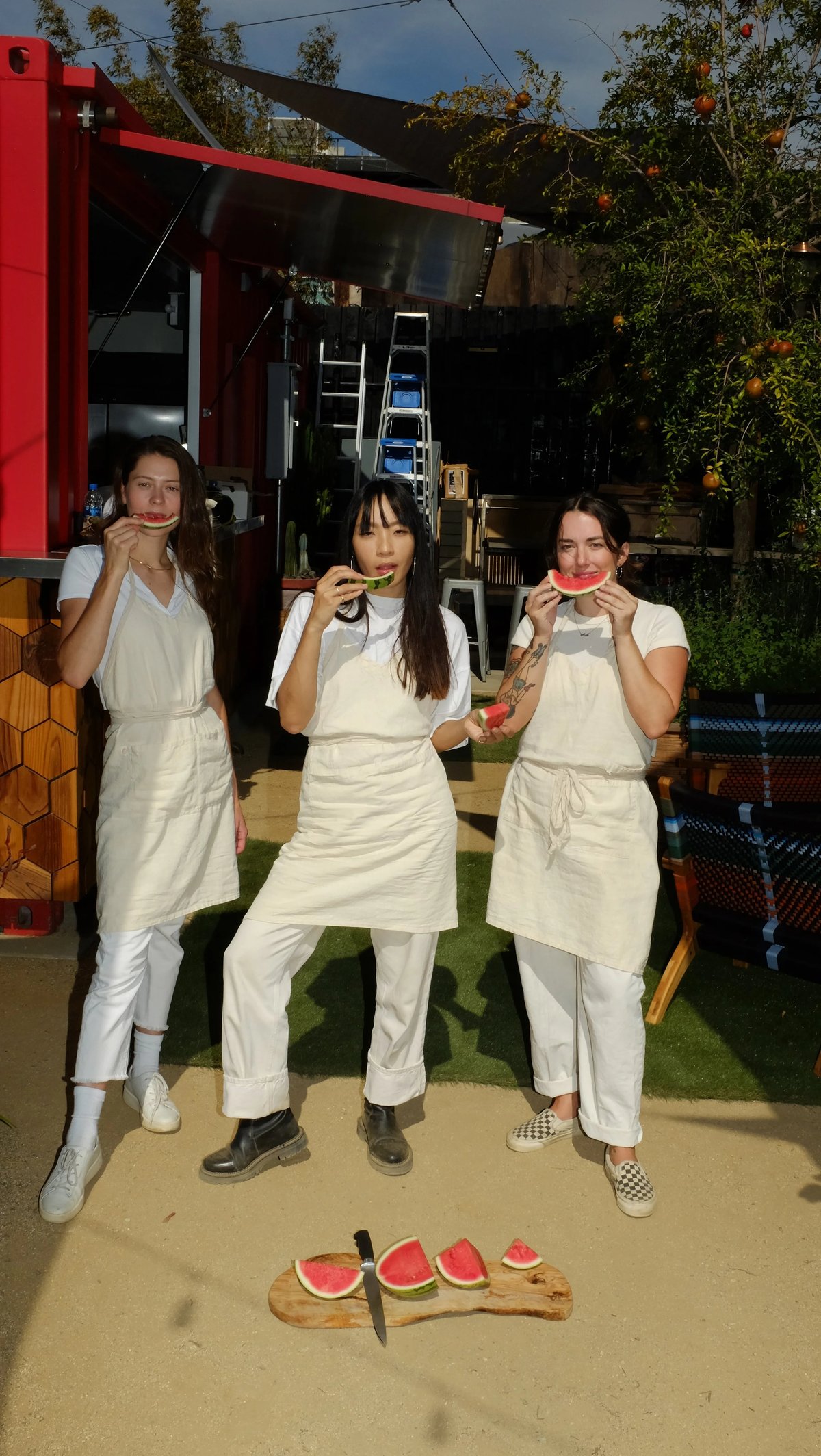 Three people standing wearing custom natural color linen apron designed by Finery.