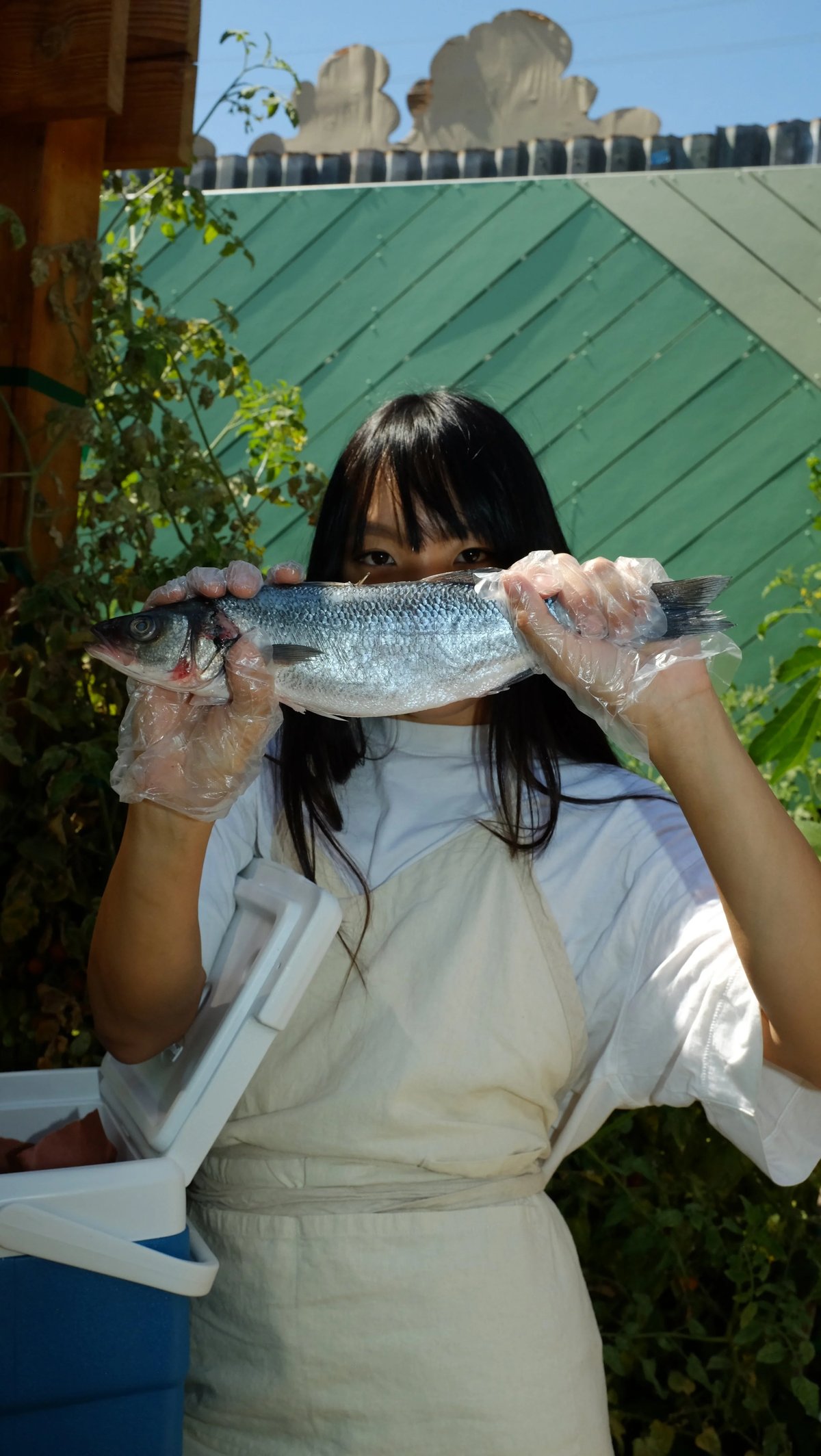 Woman holding fish wearing custom natural color linen apron designed by Finery.